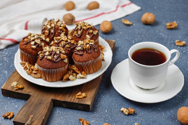 Muffins de chocolate e nozes com uma xícara de café com nozes na superfície escura