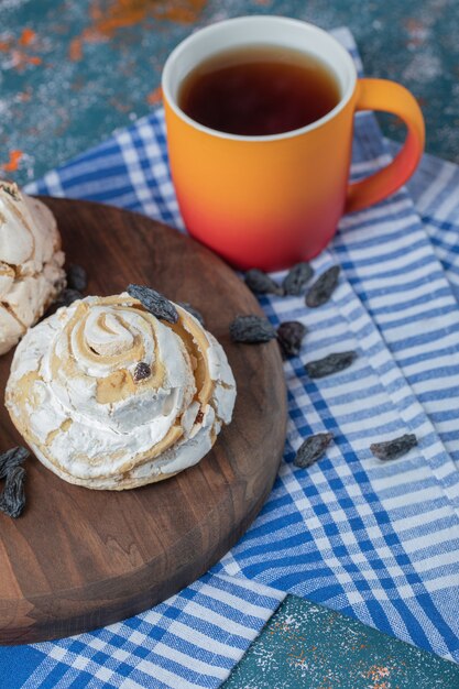 Foto grátis muffins de merengue fofos com uvas pretas secas na mesa com uma xícara de chá.