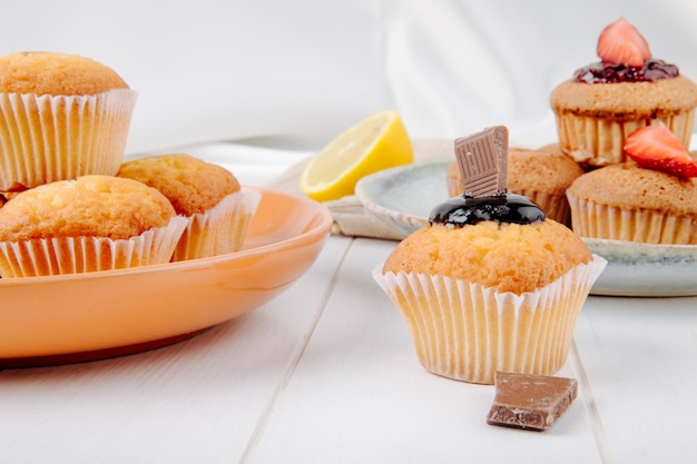 Muffins de vista frontal com chocolate e morangos em um prato com limão