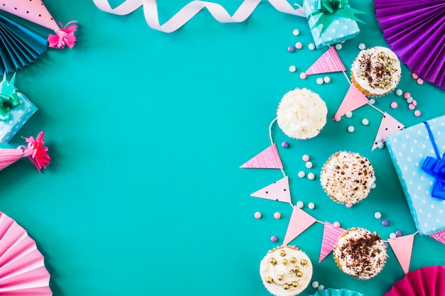 Muffins deliciosos com acessórios de festa em superfície verde