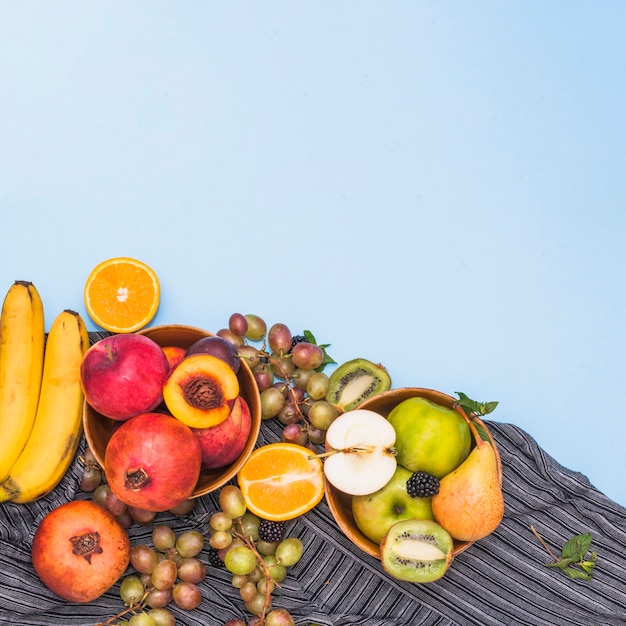 Foto grátis muitas frutas tropicais em têxteis de listras contra o fundo azul