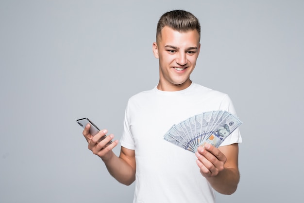 Muito jovem com uma camiseta branca segurando um monte de notas de dólar nas mãos, isoladas no branco