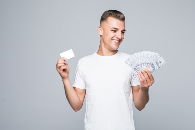 Muito jovem com uma camiseta branca segurando um monte de notas de dólar nas mãos, isoladas no branco