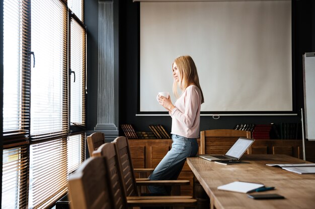 Muito jovem em pé no café trabalhar com o laptop.