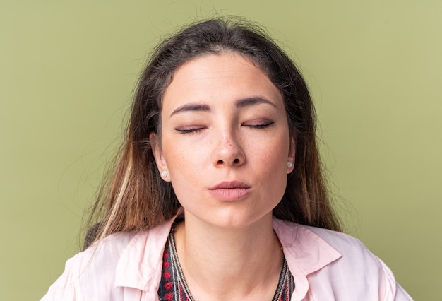 Muito jovem morena sentada com os olhos fechados, isolada na parede verde oliva com espaço de cópia