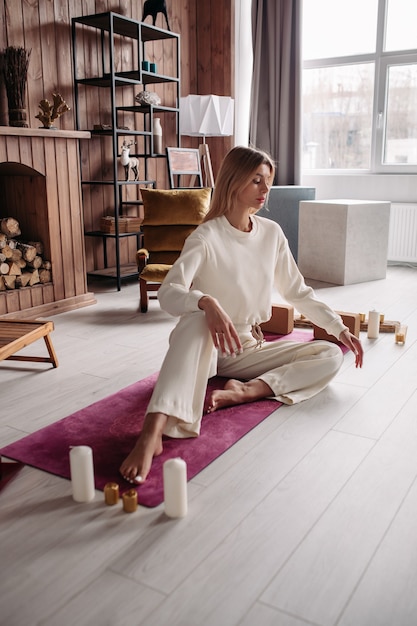 Muito jovem mulher calma meditando e relaxando sentado no tapete natural no interior aconchegante de casa no fim de semana. bem-estar da mulher.