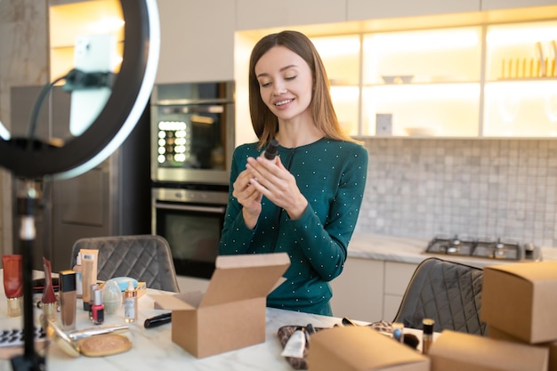 Muito jovem mulher demonstrando amostras de novos cosméticos