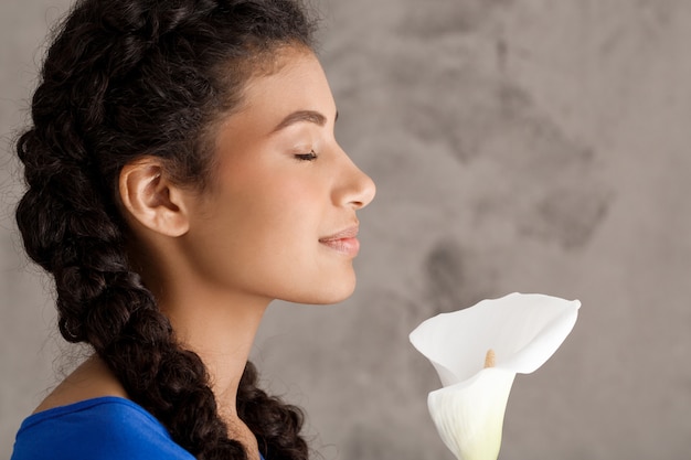 Muito jovem no perfil sorrindo, segurando flor branca