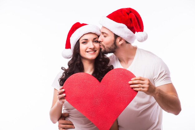 Muito jovem Santa casal amigos homem mulher Natal chapéu segurar grande coração em branco vazio isolado no estúdio de fundo branco. Conceito de feliz feriado de celebração de ano novo