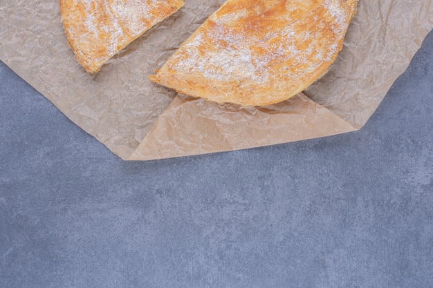 Muitos pedaços de torta deliciosa com açúcar em pó em um papel permanente