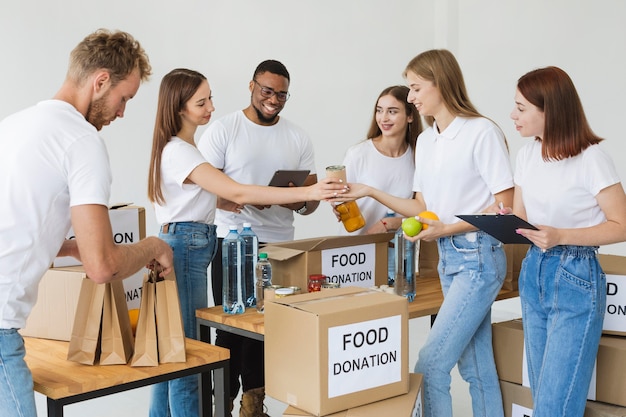 Muitos voluntários alegres preparando caixas com doações de alimentos