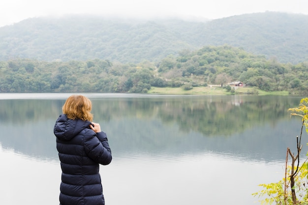 Mulher à beira do lago apreciando a vista