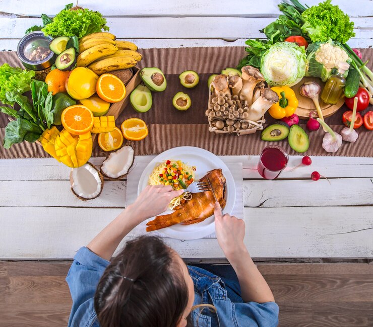 Foto grátis mulher à mesa de jantar com uma variedade de alimentos orgânicos saudáveis, vista de cima. o conceito de alimentação saudável e celebração