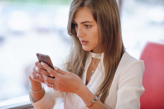 Mulher à moda com cara séria que olha seu telefone