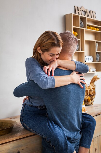 Mulher abraçando o marido na cozinha