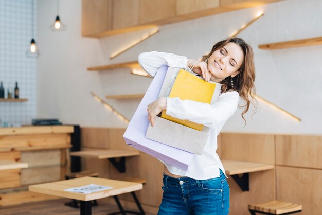 Mulher, abraçando, sacolas papel, em, café