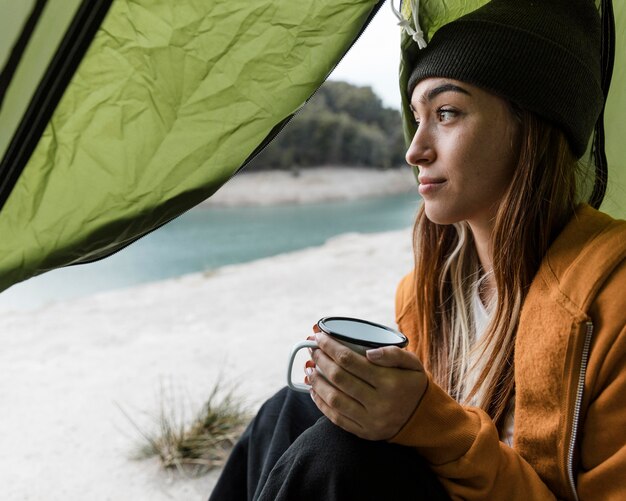 Mulher acampando e tomando uma xícara de chá