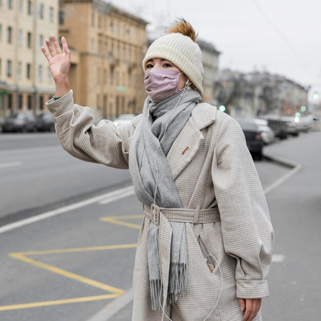 Mulher acenando na cidade usando máscara médica