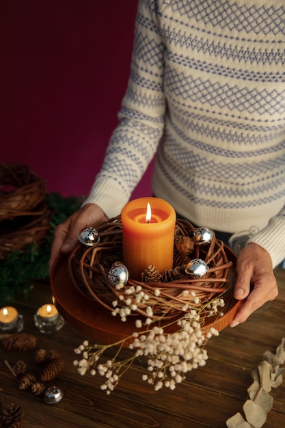 Foto grátis mulher acendendo uma vela de coroa de flores