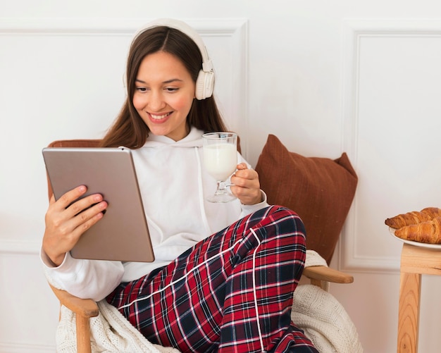 Mulher aconchegante com tablet na poltrona