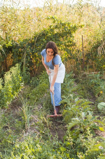 Mulher acumulando solo no campo