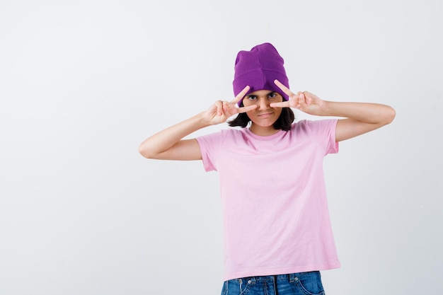 Mulher adolescente com gorro de t-shirt a mostrar gesto de vitória
