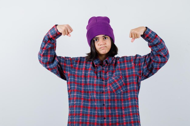 Mulher adolescente de camisa xadrez e gorro gesticulando isolada