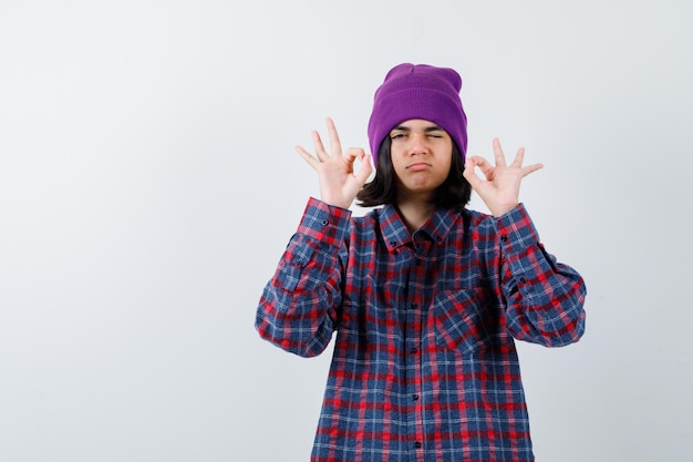 Mulher adolescente de camisa xadrez e gorro gesticulando isolada