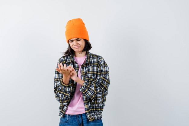 Mulher adolescente de camisa xadrez e gorro gesticulando isolada