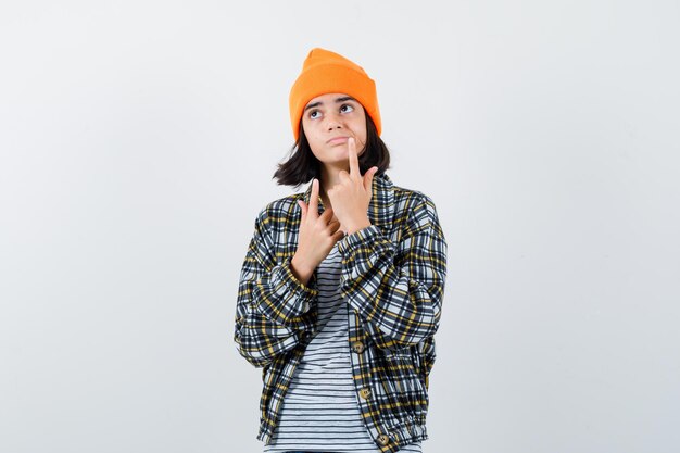 Mulher adolescente de camisa xadrez e gorro gesticulando isolada