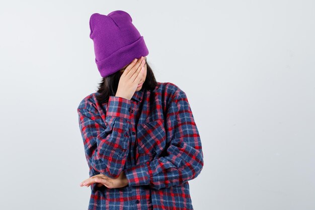 Mulher adolescente de camisa xadrez e gorro gesticulando isolada