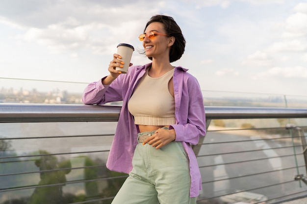 Foto grátis mulher adorável com penteado curto caminhando na ponte moderna em um dia ventoso de verão