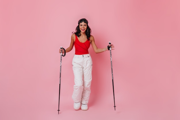 Mulher adorável sorridente posando com bastões de esqui