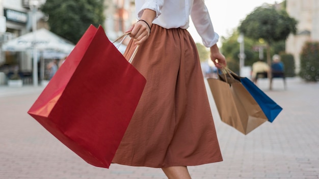 Mulher adulta carregando sacolas de compras coloridas