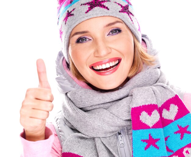 mulher adulta feliz com roupas de inverno com emoções positivas brilhantes mostrando sinal de polegar para cima isolado no branco