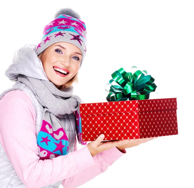 mulher adulta feliz dando um presente de natal em um casaco de inverno isolado no branco