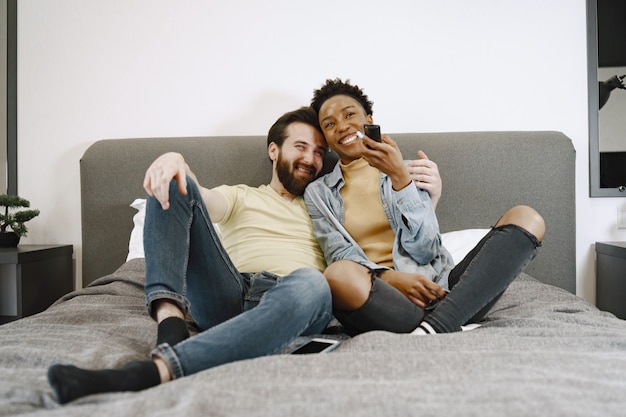 Mulher africana assistindo tv. Homem e menina na cama. Cara com barba.