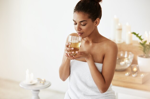 mulher africana bebendo chá verde descansando no salão spa.