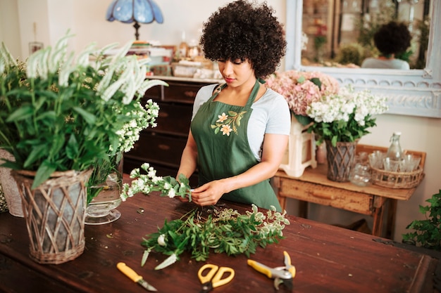 Mulher africana, classificando as plantas de flor na mesa de madeira