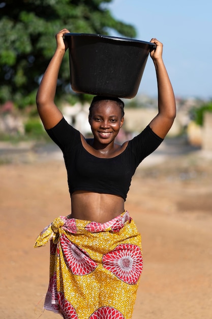 Foto grátis mulher africana com um balde de água na cabeça