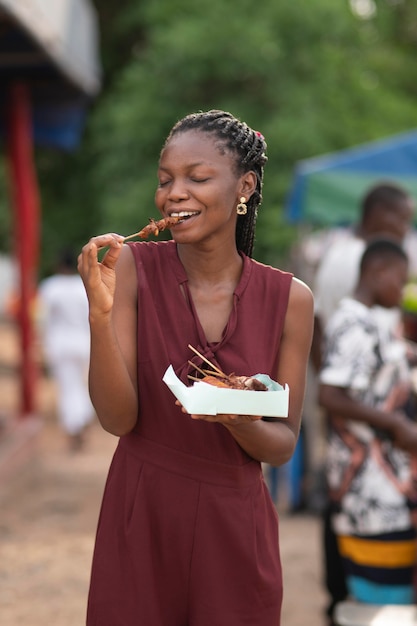 Foto grátis mulher africana comendo comida de rua