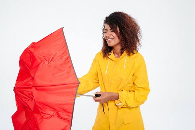 Mulher africana confusa na capa de chuva fechar guarda-chuva