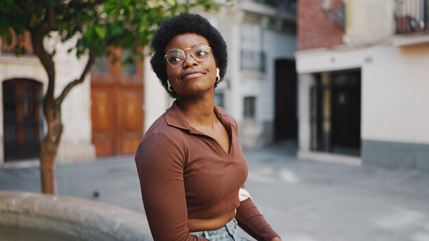 Mulher africana em óculos desfrutando de uma caminhada pela rua Pr