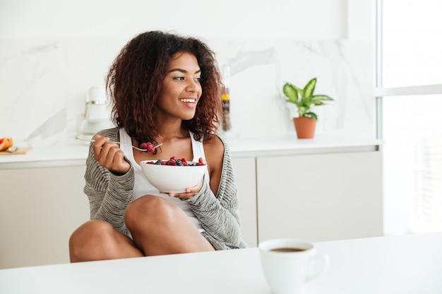 Foto grátis mulher africana muito sorridente comendo pela mesa