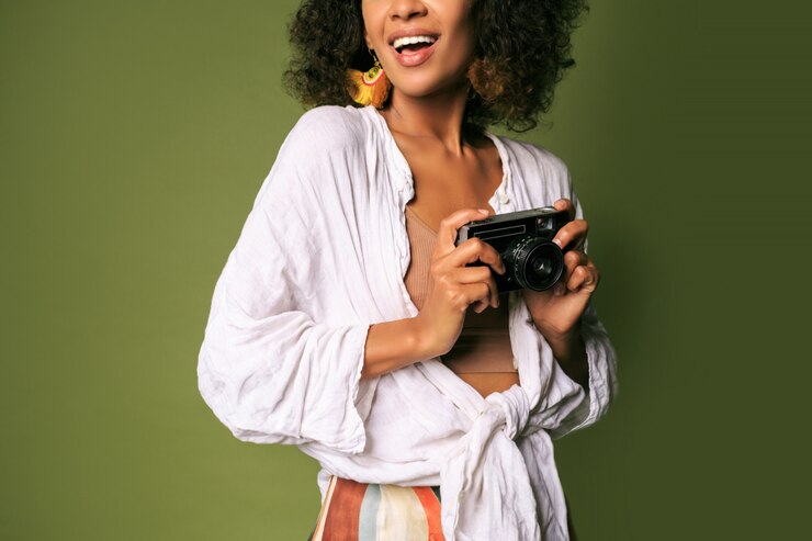 Foto grátis mulher africana segurando a câmera fotográfica retrô e rindo.
