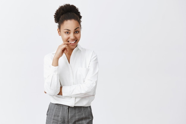 Mulher afro-americana atrevida e atenciosa sorrindo satisfeita pensando em uma ótima ideia de negócio