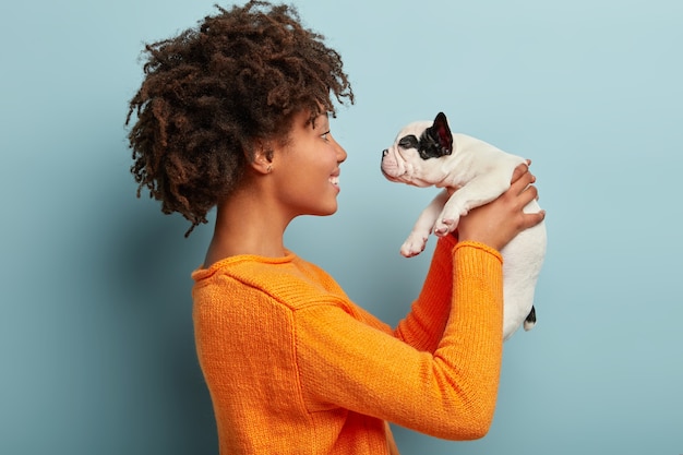 Mulher afro-americana com suéter laranja segurando cachorro