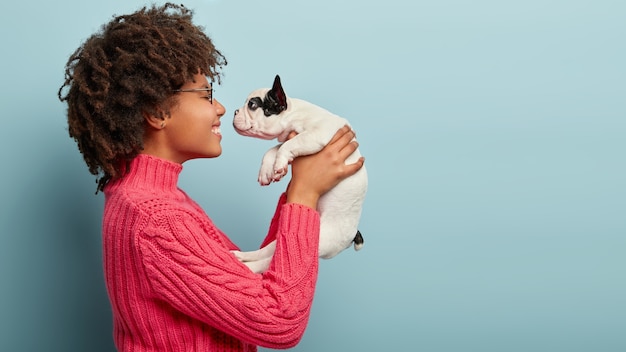 Foto grátis mulher afro-americana com suéter rosa segurando cachorro