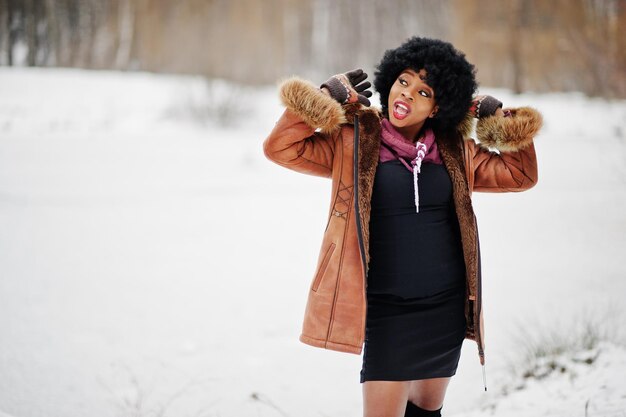 Mulher afro-americana de cabelo encaracolado usa casaco de pele de carneiro e luvas posadas no dia de inverno