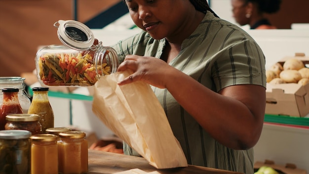 Mulher afro-americana derrama massa em saco biodegradável